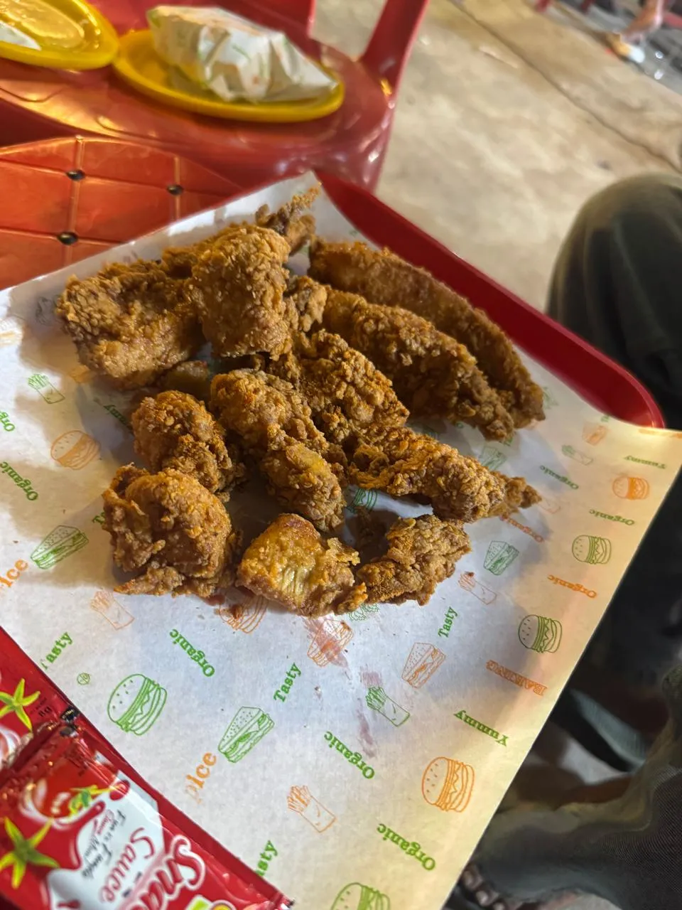 Fresh, crispy Broast Nation chicken strips on a red tray at the stall